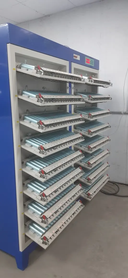 A blue testing cabinet with shelves of cylindrical cells on charge and discharge trays